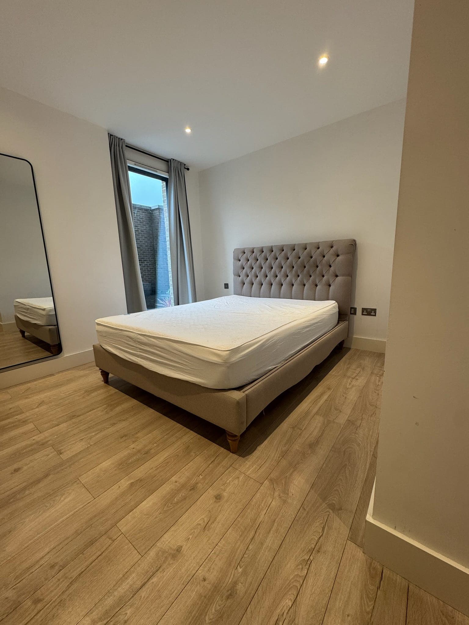 The main bedroom with a full-height window and a floor-standing mirror