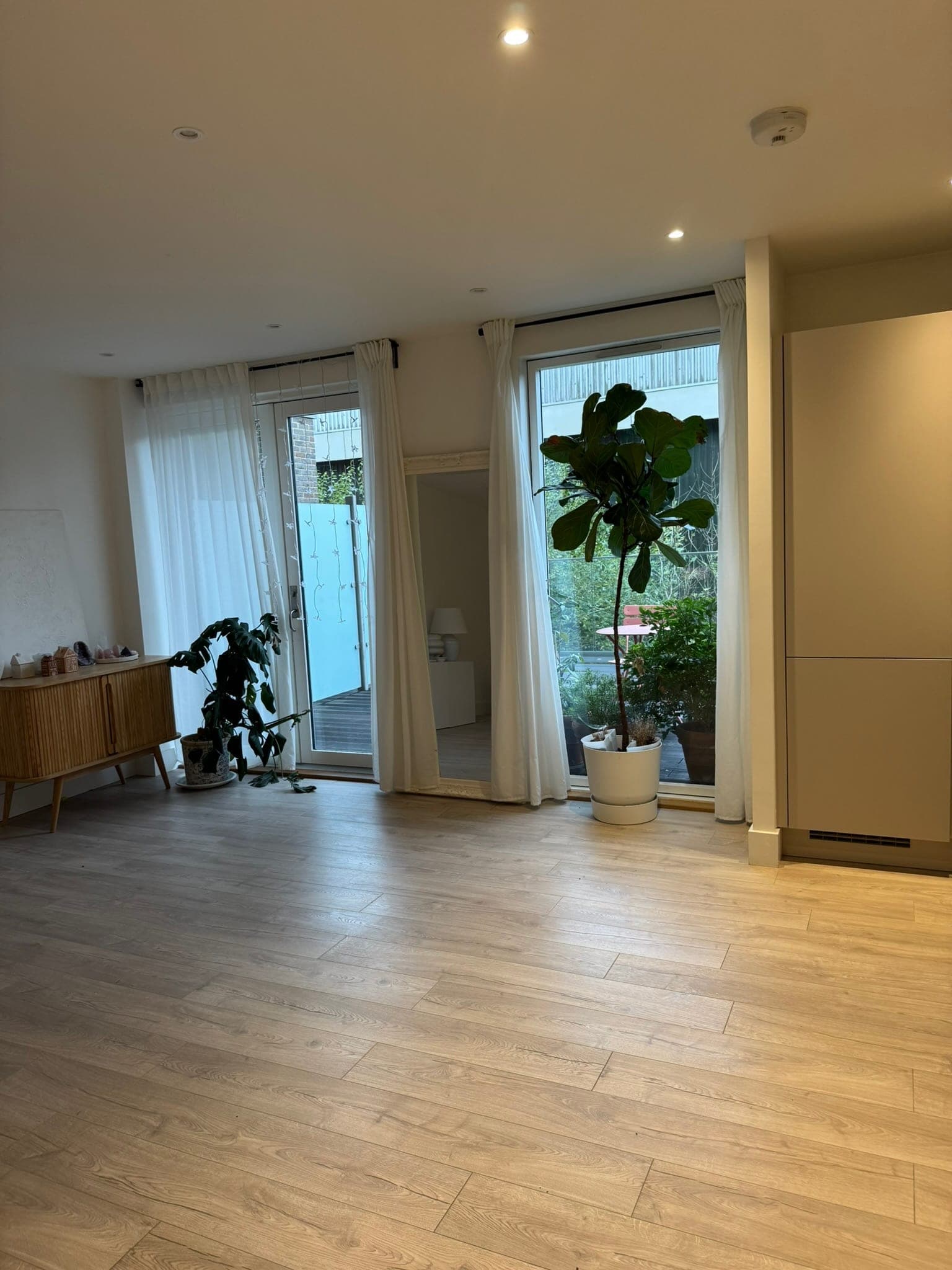The living and dining space with full-height windows and doors opening onto the terrace